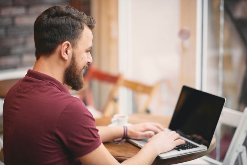 middle aged man working on his laptop from a cafe