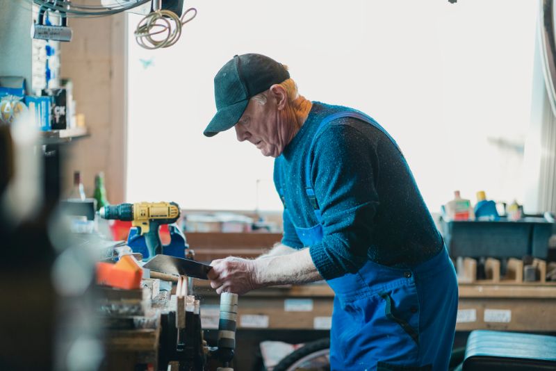 old man pursuing woodworking hobby in his free time.
