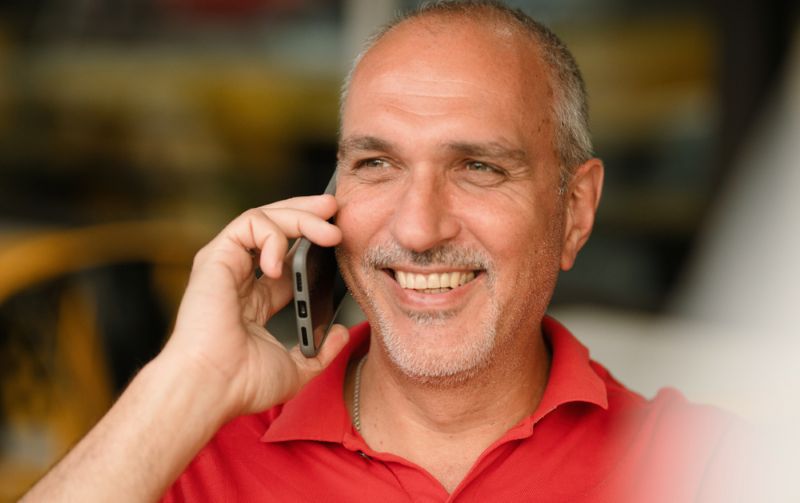 Older man in a red shirt taking a phone call