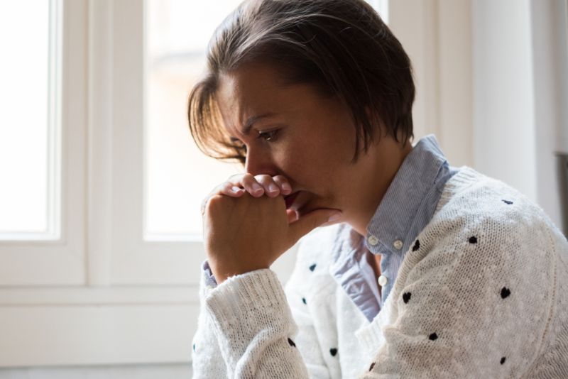 Concerned older woman with her hands clasped