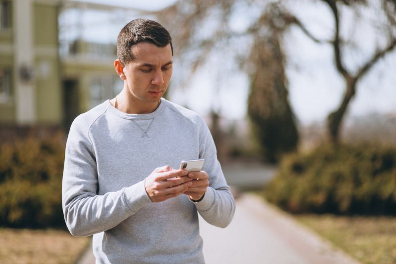 Man walking outside while scrolling on his phone