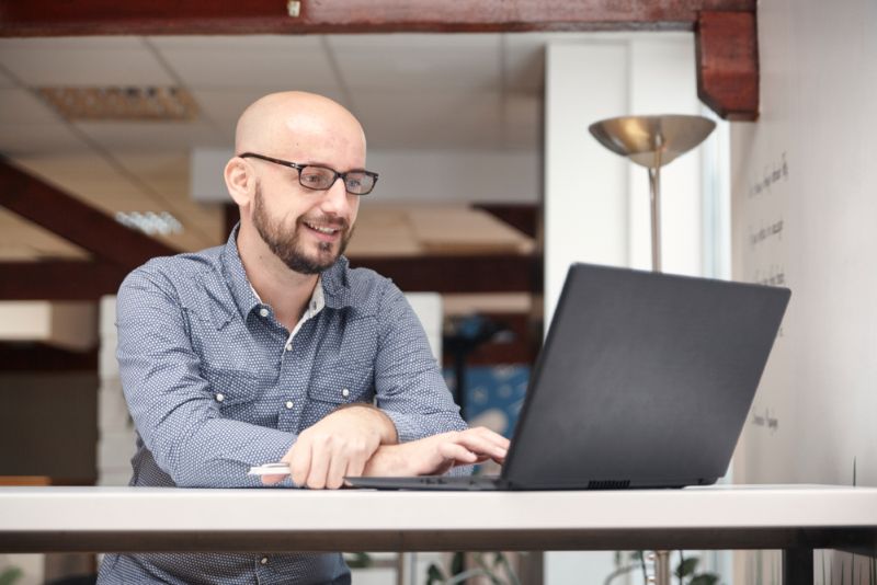 Bald veteran researching on his personal laptop