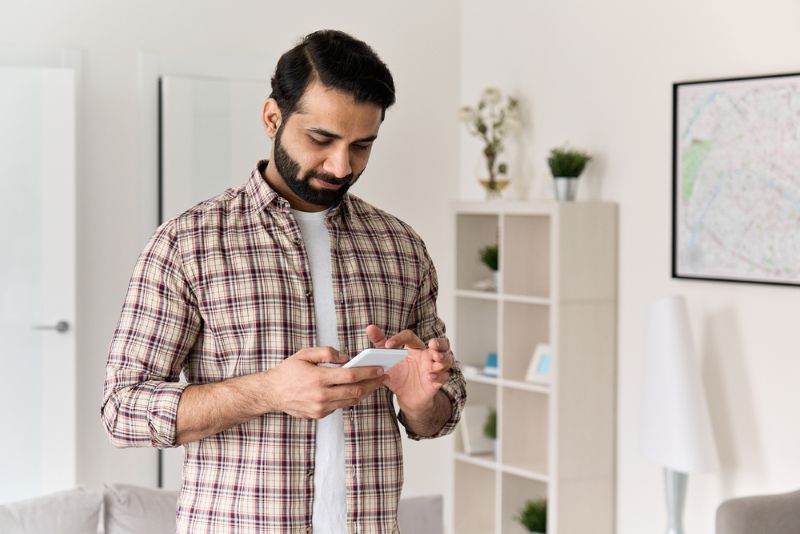 Man with a beard scrolling on his phone from home